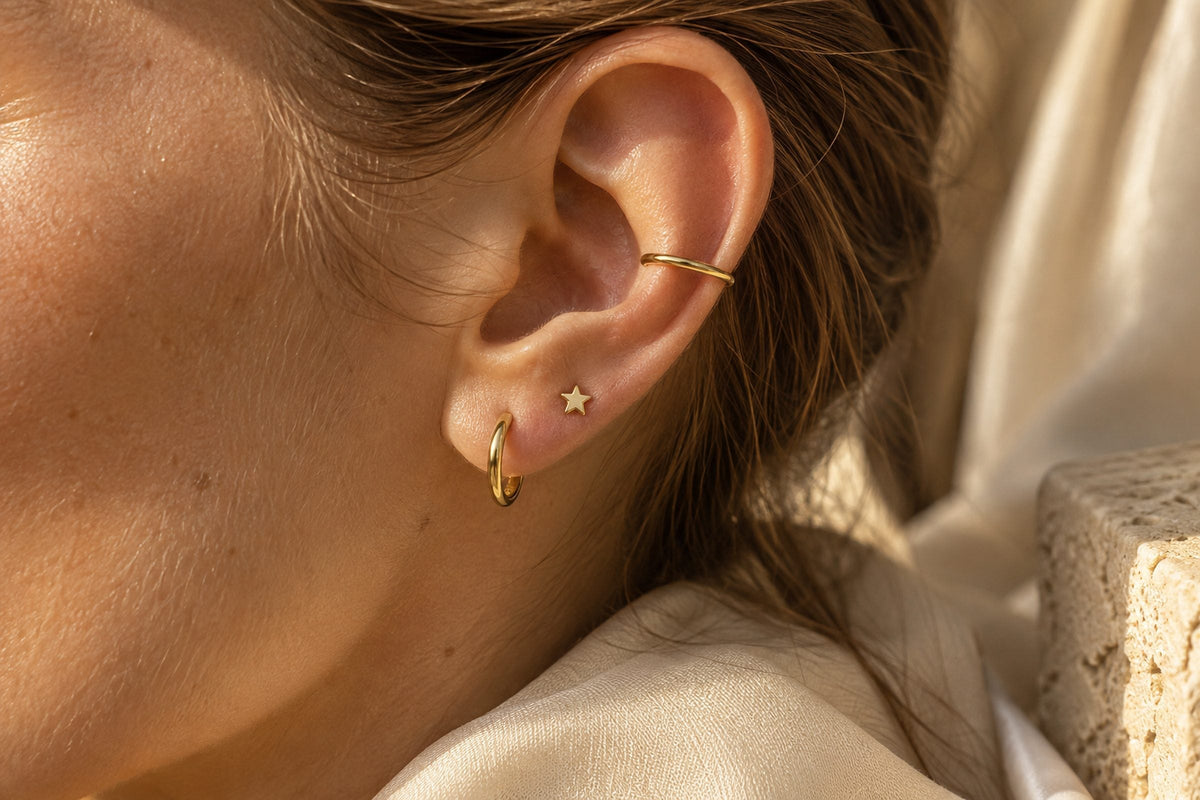 Oreille en gros plan avec trois bijoux dorés superposés